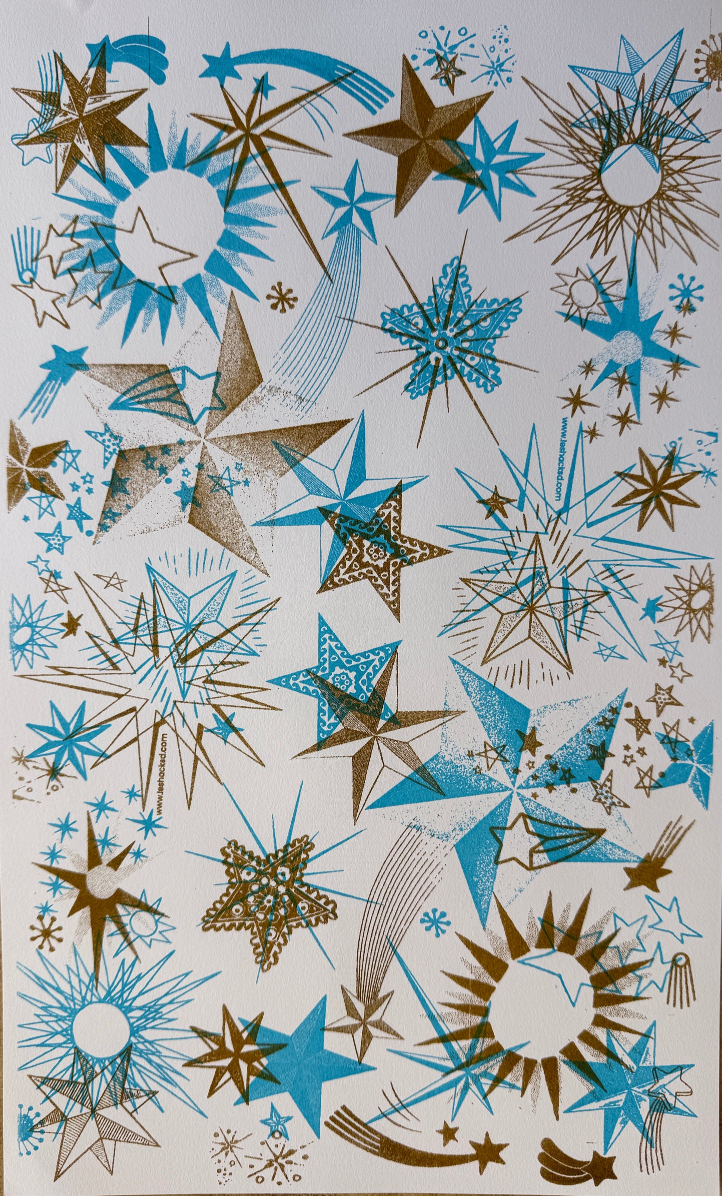 riso print on cardstock of images of stars in layers of ink in aqua and gold ink